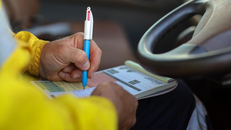 Someone sitting in a car, filling out a form